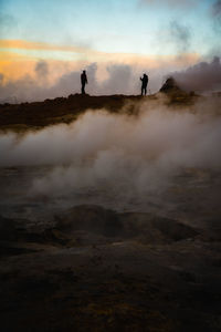 Silhouette people standing on land against sky during sunset