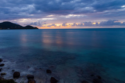 Scenic view of sea against cloudy sky during sunset