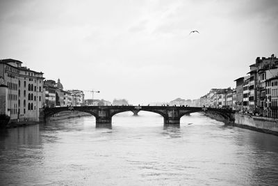 Bridge over river in city against sky