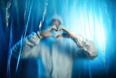 Doctor makes a heart with his hands inside covid ward. coronavirus hospital.