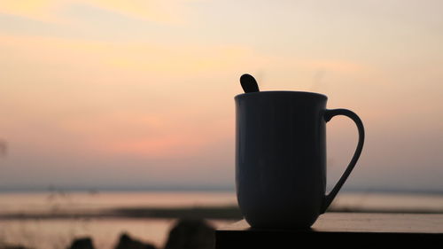 Close-up of silhouette coffee cup against sky during sunset