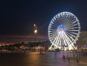 Illuminated ferris wheel against clear sky at night