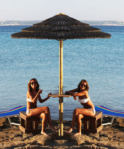 Multiple image of woman wearing bikini while sitting on rocky shore