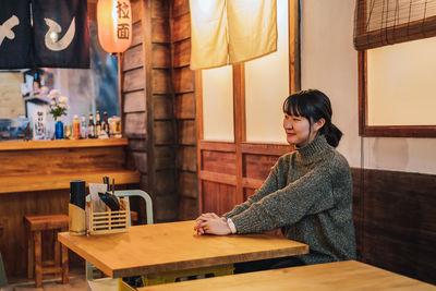 Young woman sitting on table at cafe