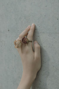 Cropped hand of young woman with rose shape rings on wall