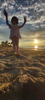 Rear view of woman standing on beach during sunset