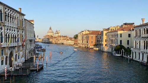 Boats in canal amidst buildings against clear sky