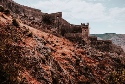 Old building by mountain against sky