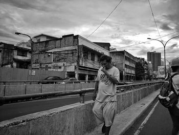 Man standing on street in city against sky