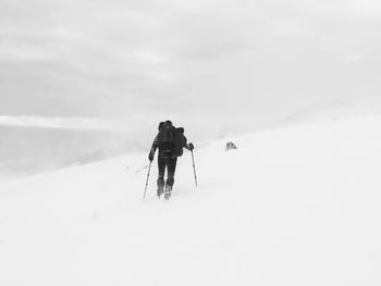 People skiing on snow covered landscape against sky