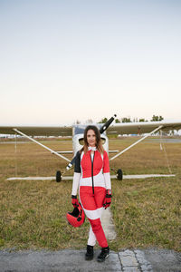 Young female skydiver in an airfield with a plane behind her