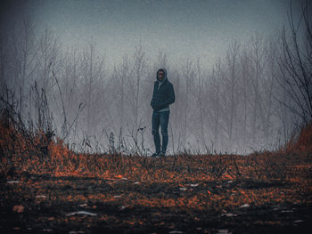Man standing on field against trees in forest