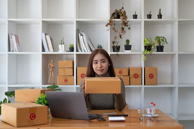 Portrait of young woman using phone while sitting on table