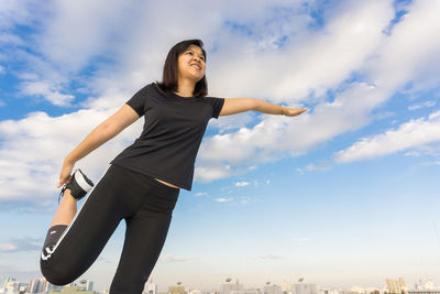 Low angle view of woman standing in city against sky