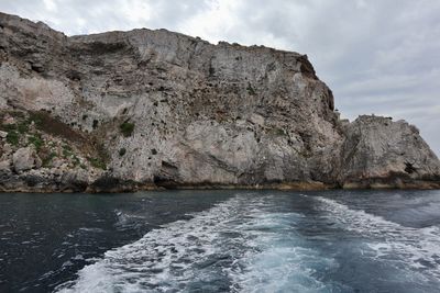 Rock formation by sea against sky