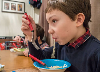 Close-up of boy eating noodles while sitting at table