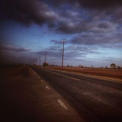 Road passing through landscape against cloudy sky