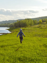 Rear view of woman walking on field against sky