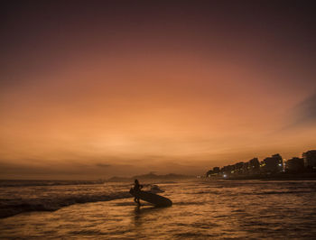 Surfer sunset at barra da tijuca beach, rio de janeiro