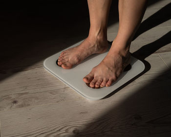 Low section of woman standing on weigh scale