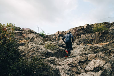 Low angle view of sportsman climbing rocks on hill