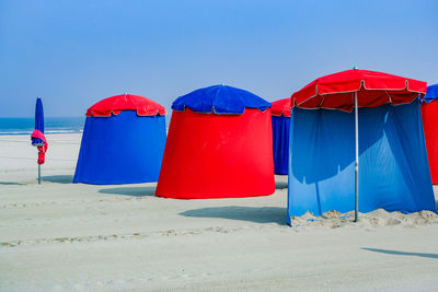 Multi colored umbrellas on beach against clear blue sky
