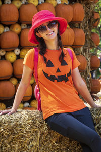 Portrait of smiling woman standing against pumpkins