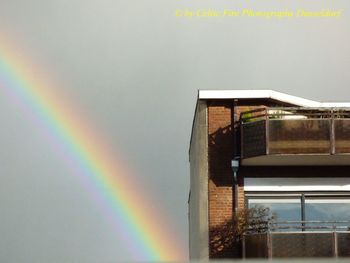 Low angle view of rainbow over building against sky