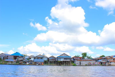 Houses by river against sky