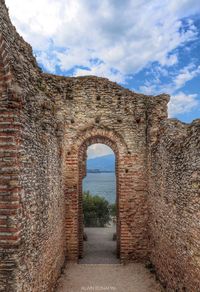 Archway of historical building against cloudy sky