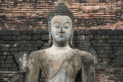 Statue of buddha against brick wall