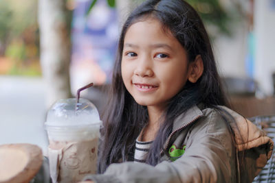 Portrait of girl with milkshake sitting at restaurant