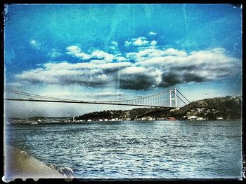 Bridge over river against cloudy sky