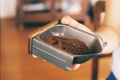 Midsection of woman holding ground coffee in container