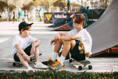 Two best friends in a skateboard park. friends sit on skates in the park, talking and smiling. 