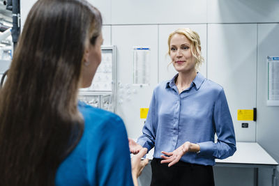 Businesswoman discussing with coworker at automated factory