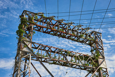 Low angle view of electricity pylon against clear blue sky