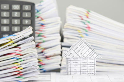 Close-up of model house with calculator on financial documents against gray background