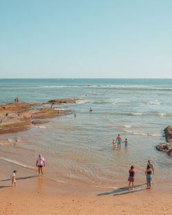 People on beach against clear sky
