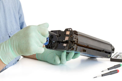 Cropped image of person repairing machinery at table against white background