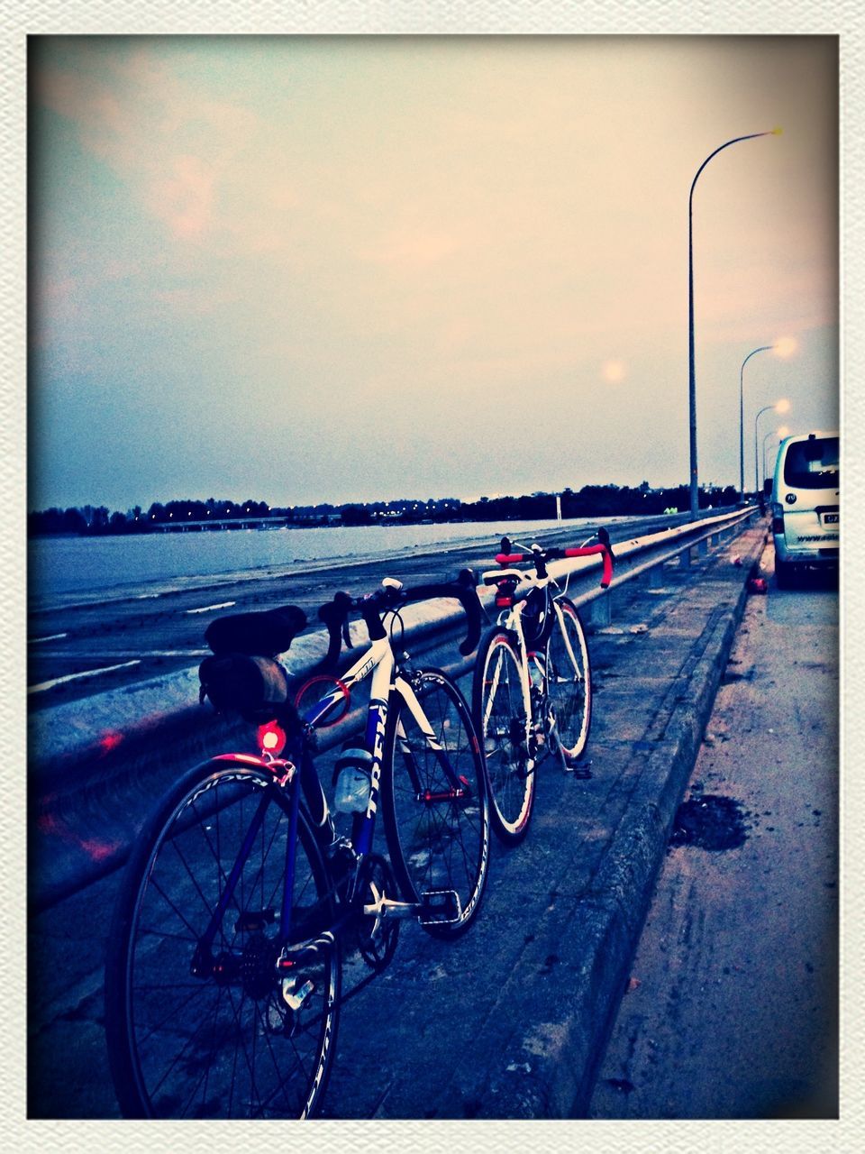 transportation, bicycle, mode of transport, land vehicle, parked, stationary, parking, street, transfer print, sky, auto post production filter, road, car, travel, parking lot, cloud - sky, outdoors, cycling, side view, no people