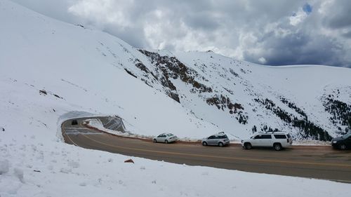 Cars moving on road by snow covered mountain