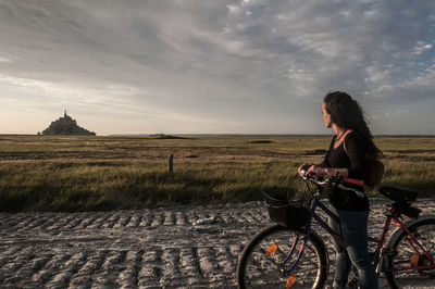 Full length of woman with bicycle on field against sky