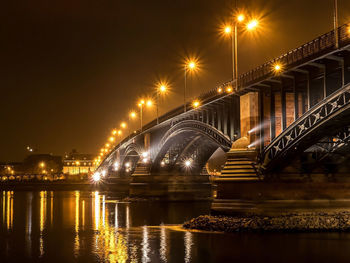 Illuminated bridge over river at night