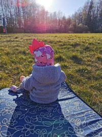 Rear view of girl sitting on field during winter