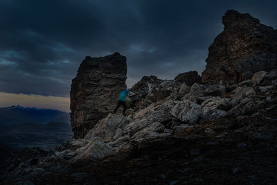 Rear view of man standing on rock against sky during sunset