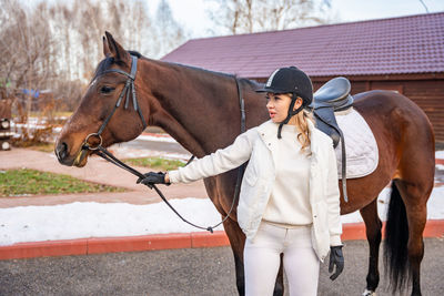 Side view of woman standing with horse