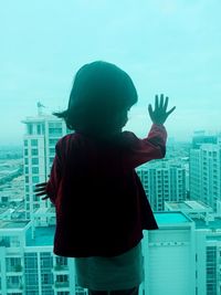 Rear view of woman standing against buildings in city