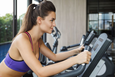 Side view of young woman using mobile phone in gym