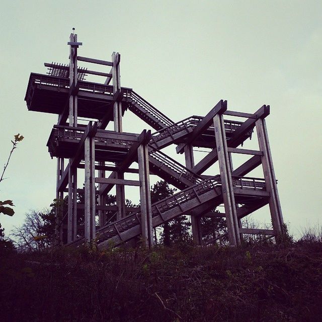 clear sky, low angle view, built structure, sky, architecture, copy space, metal, metallic, outdoors, day, connection, no people, nature, wood - material, tree, field, sunlight, abandoned, old, building exterior